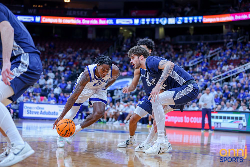 College basketball player drives past a defender during an intense Big East conference basketball game.