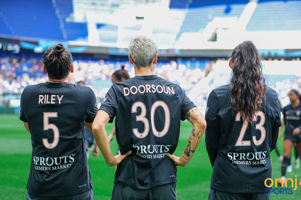 Three NWSL players wearing Riley 5, Doorsoun 30, and number 23 Sprouts-sponsored jerseys on field.