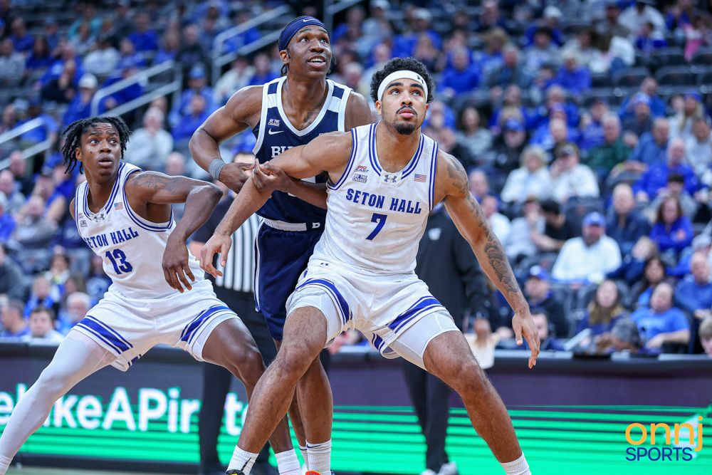 Seton Hall basketball player #7 boxes out opponent under the basket during a college basketball game.