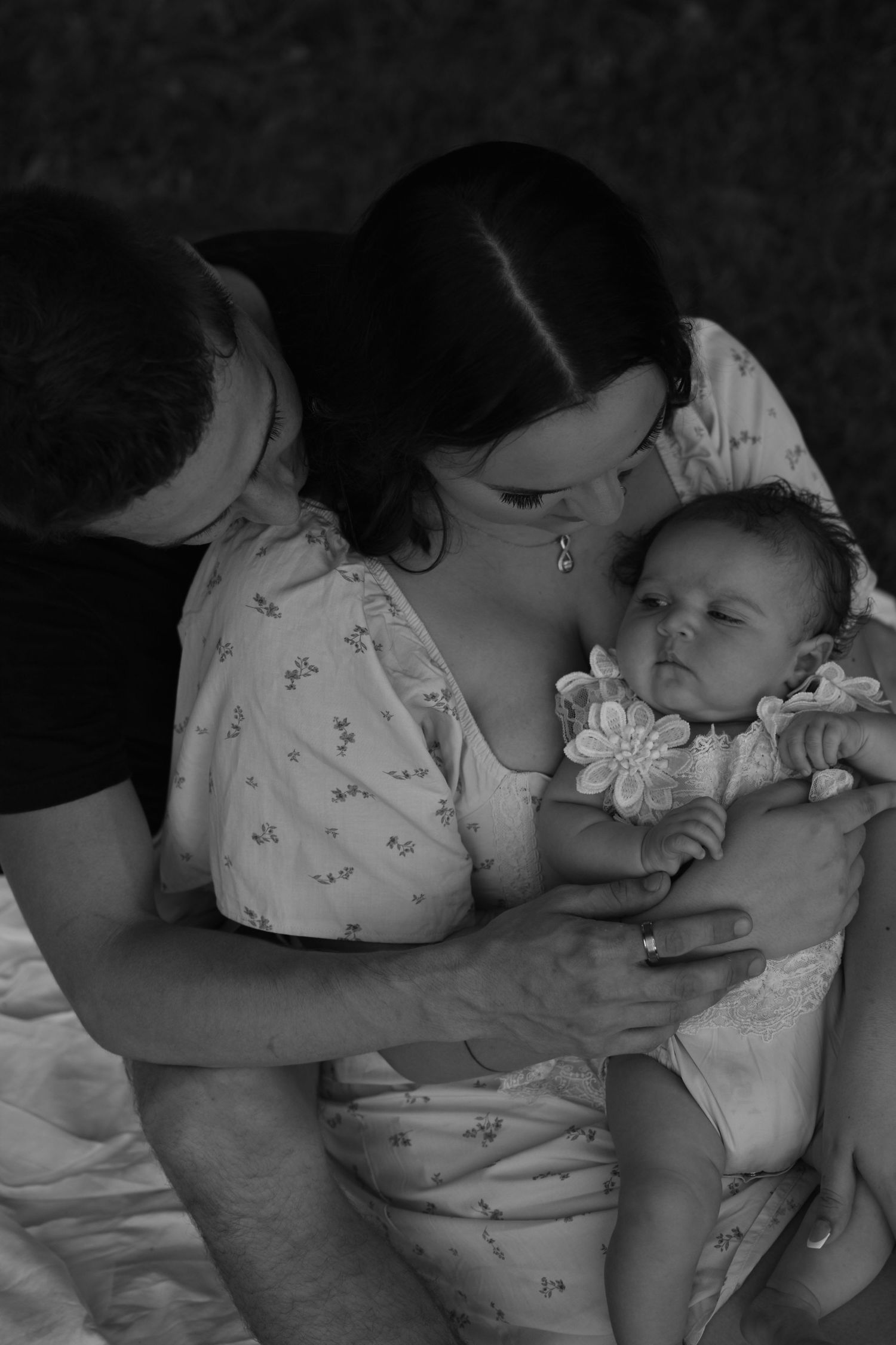 Black and white photo of parents lovingly gazing at their newborn baby, a tender family portrait.