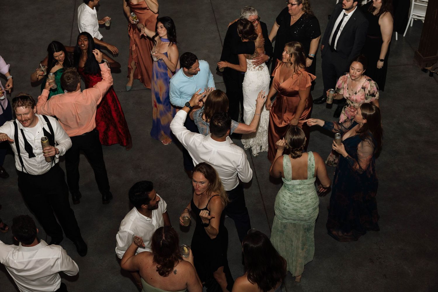 Overhead view of wedding guests dancing and celebrating on the dance floor at a reception.