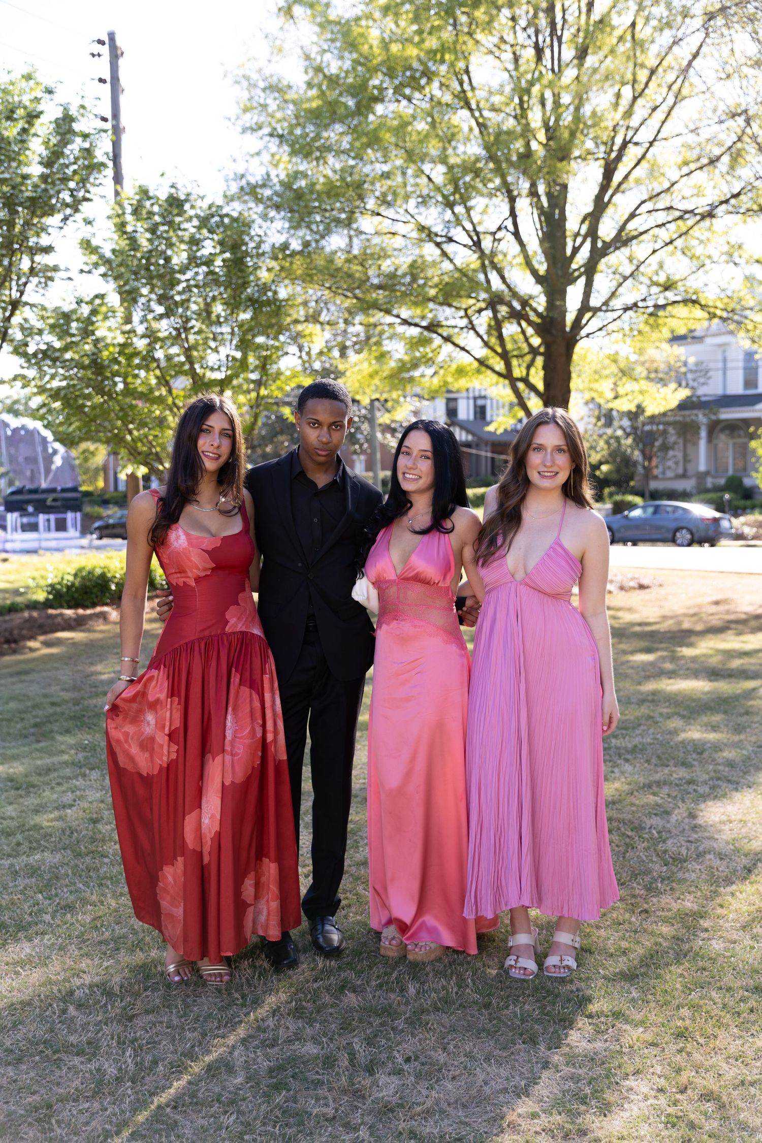 Group of four young adults in formal attire posing outdoors at a prom or wedding event.