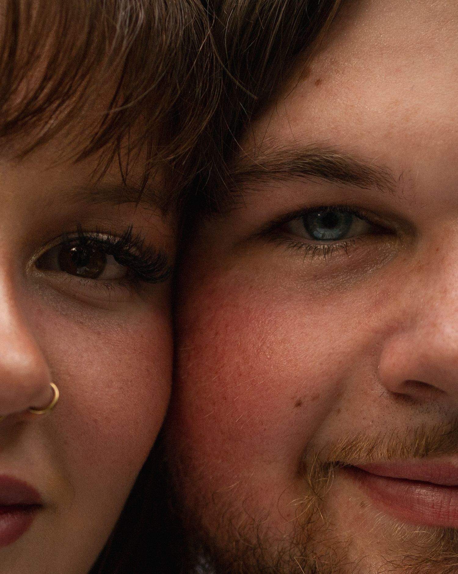 Close-up portrait of a couple with blue and brown eyes cheek to cheek.