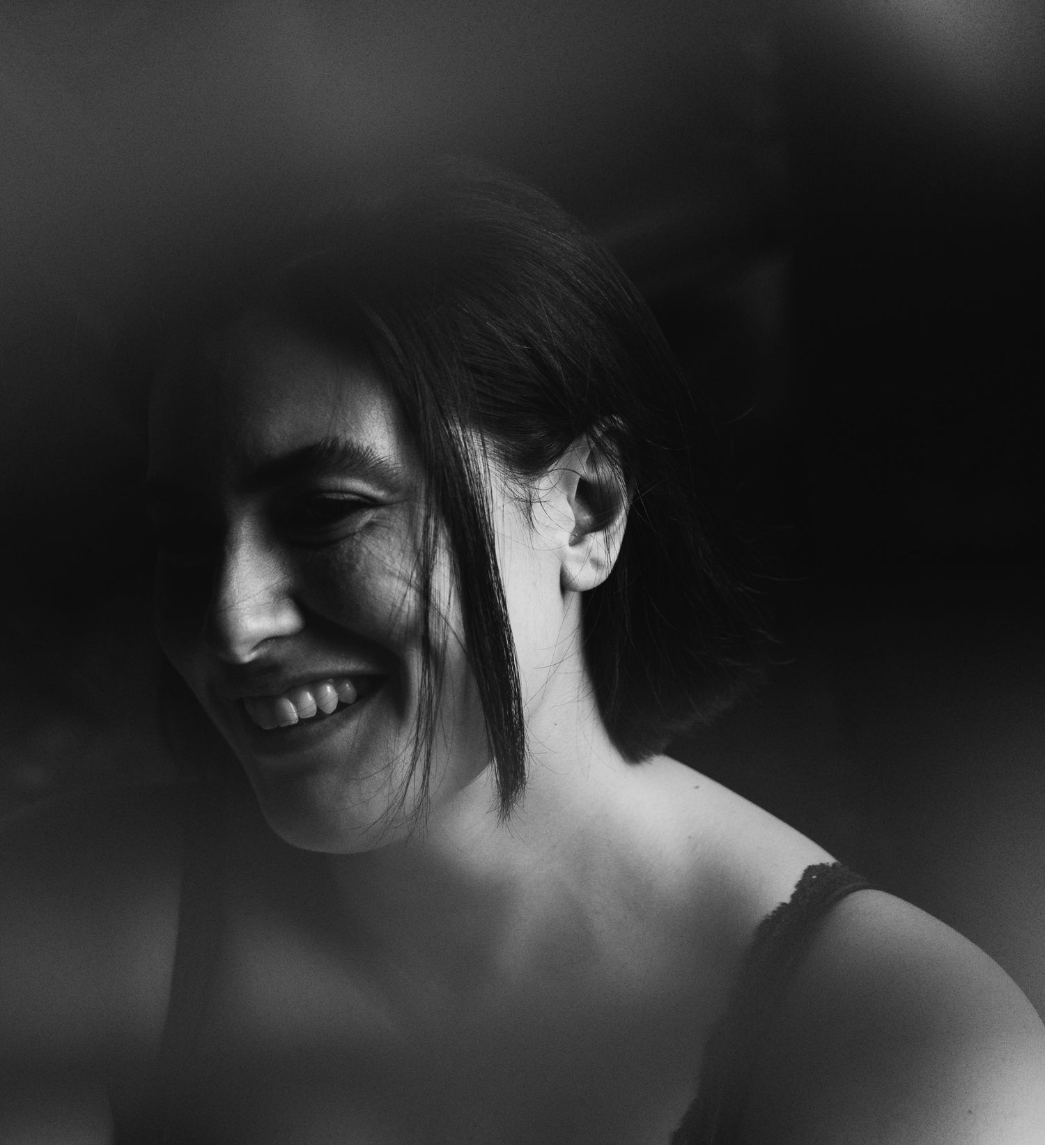 Black and white portrait of a smiling dark-haired woman with hair across her face.