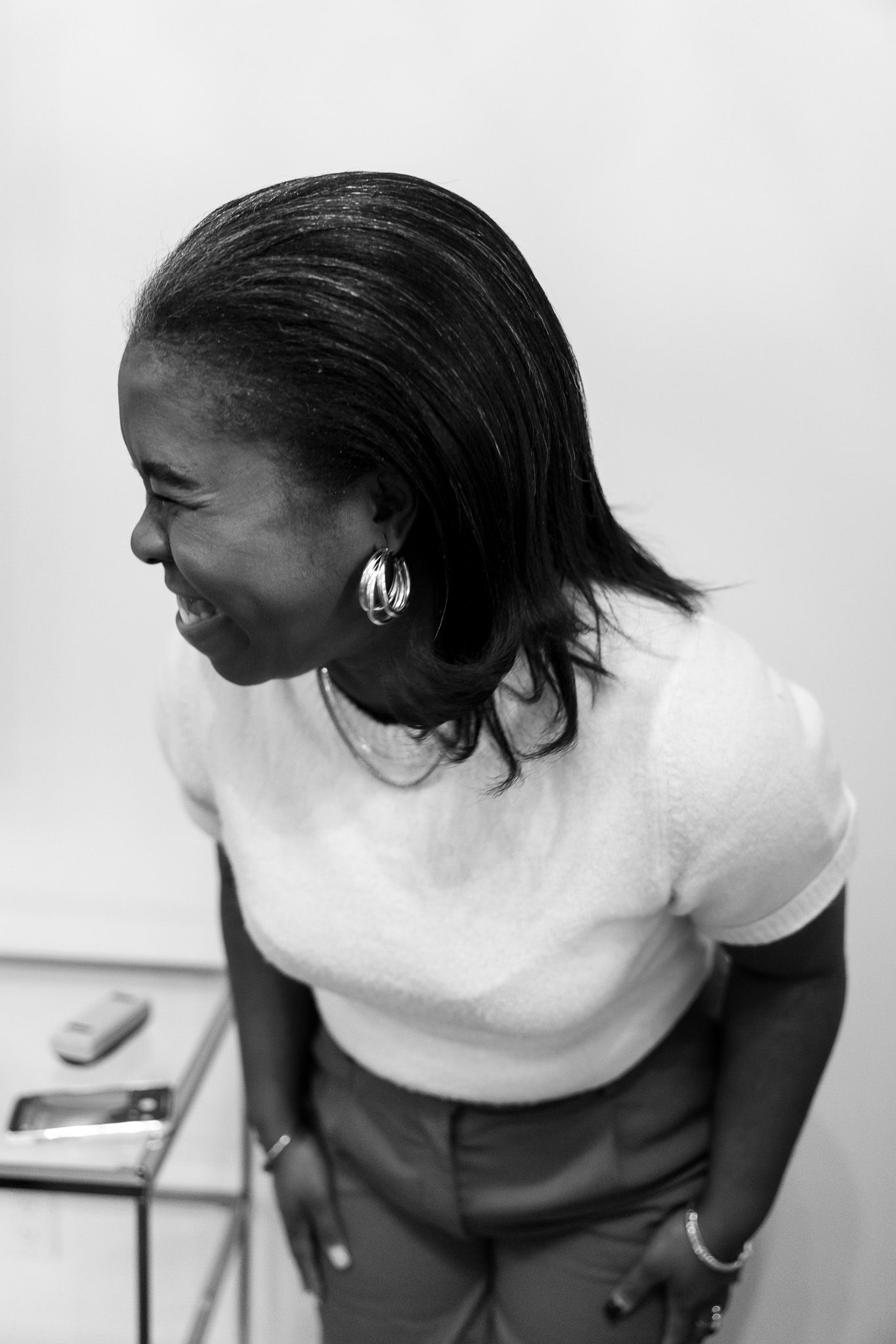 Black and white portrait of a smiling woman in a white top and hoop earrings, looking to the side.