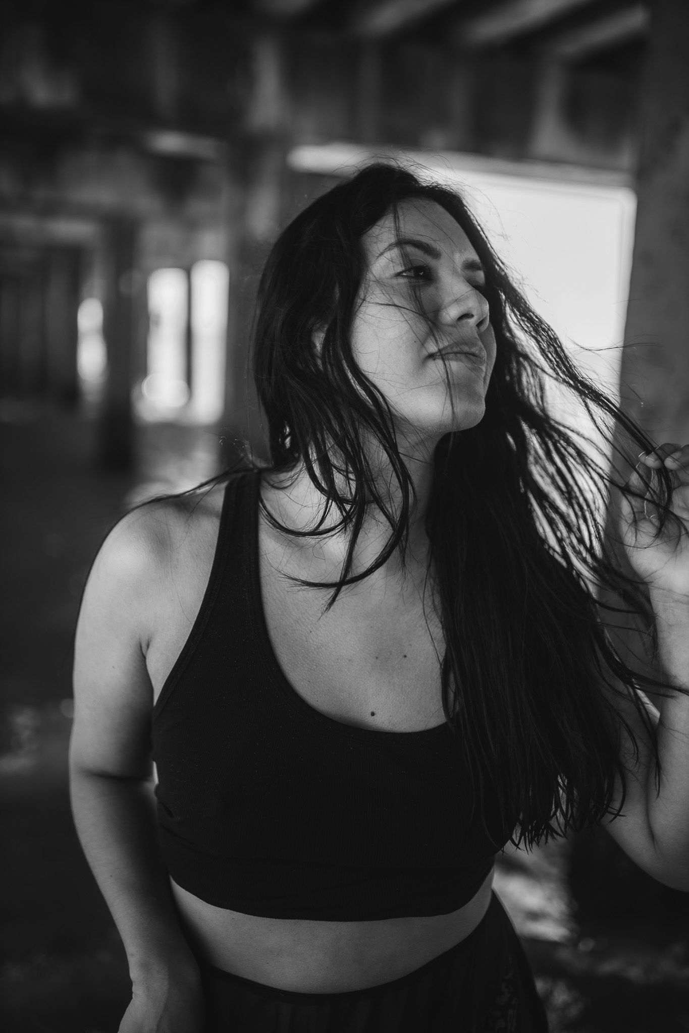 Dramatic black and white photo of woman with windblown hair in black crop top.