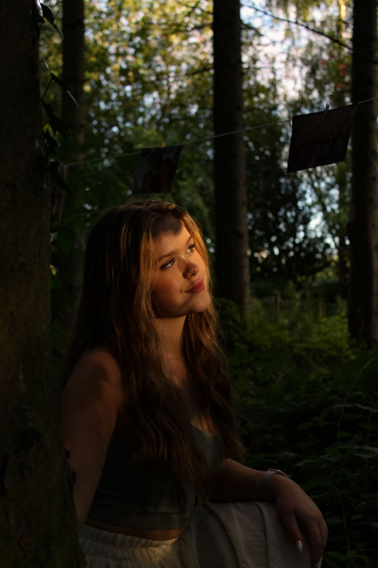 Beautiful portrait of a woman crouched in a forest. Golden hour lighting.