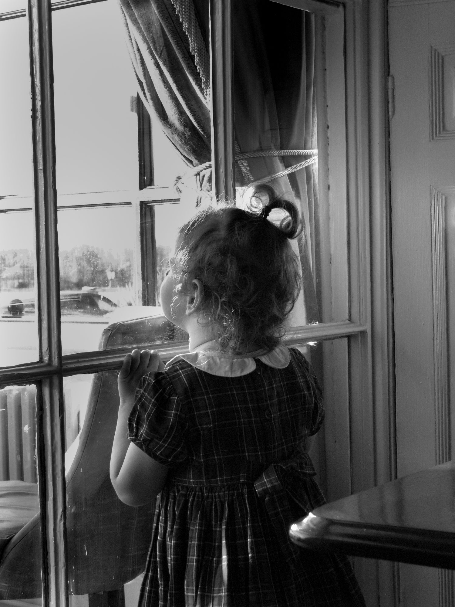 Child looking out of a window. Family photoshoot. Black and white.