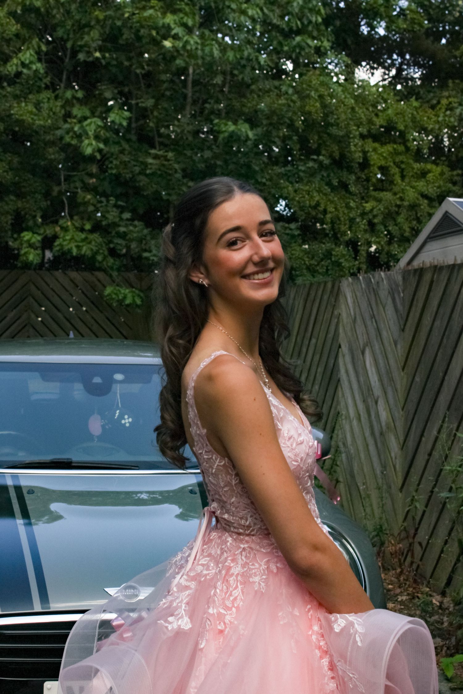 Prom portrait photo of a girl wearing her pink prom dress and smiling.