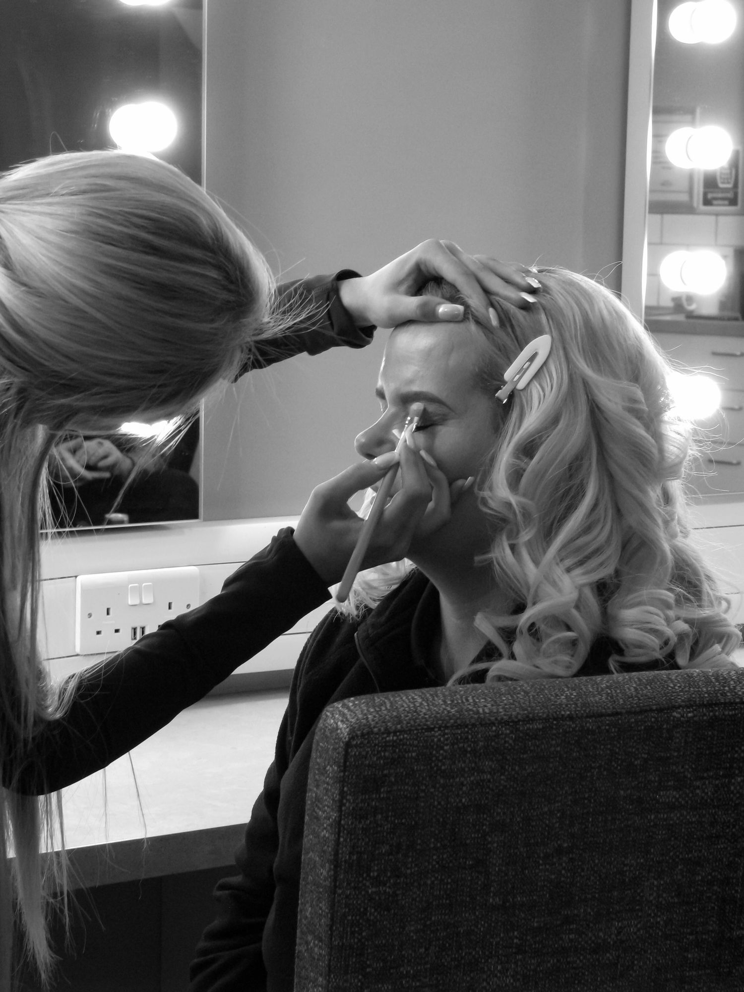 Action photo of a makeup artist doing her clients makeup. Black and white.
