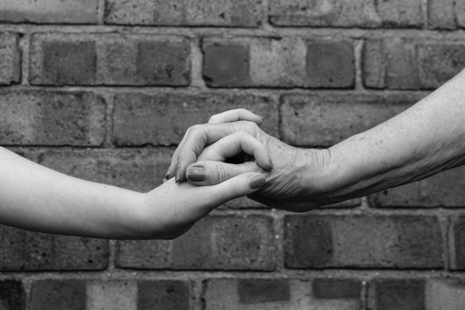 A grandparent and grandchild holding hands. Black and white.