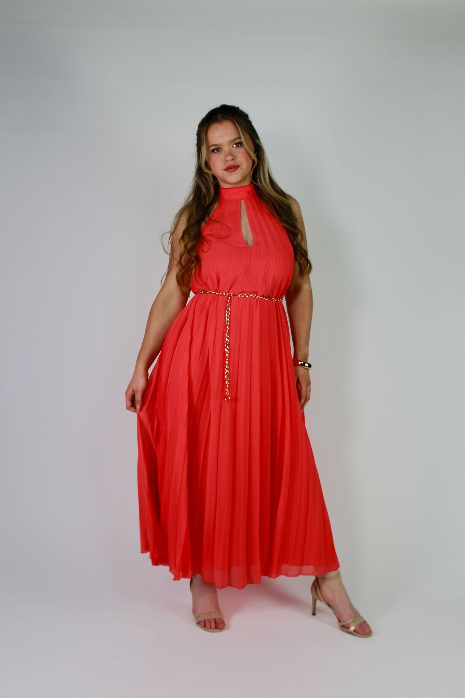 Studio portrait of a woman holding her dress. Fashion photo. Wearing a pink dress. Hair half up.