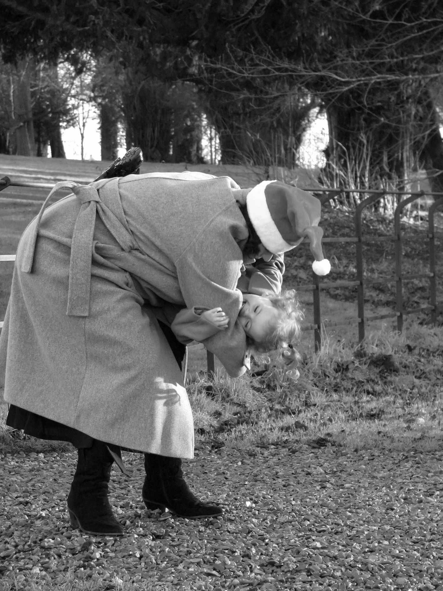 A mother hugging her daughter. Both are smiling and wearing Santa hats. Family photoshoot. Black and white.