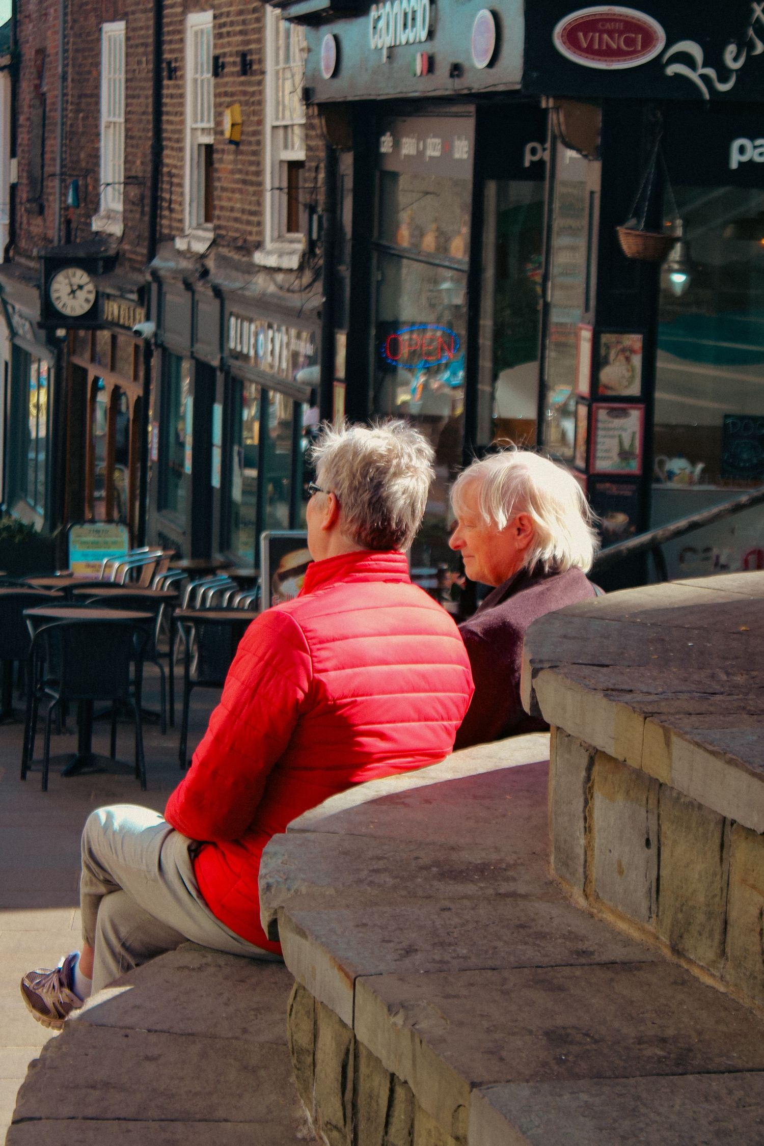 Street photography. Photo of two women sat on steps and chatting in Durham.