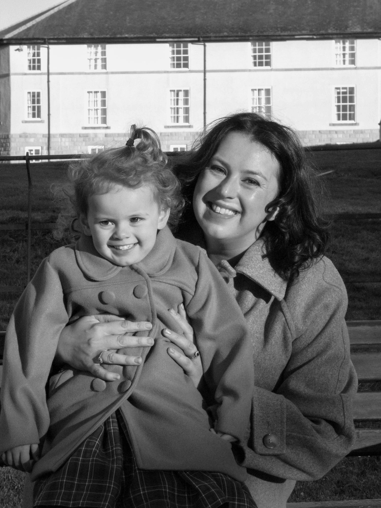 A mother hugging her daughter. Both are smiling. Family photoshoot. Black and white.