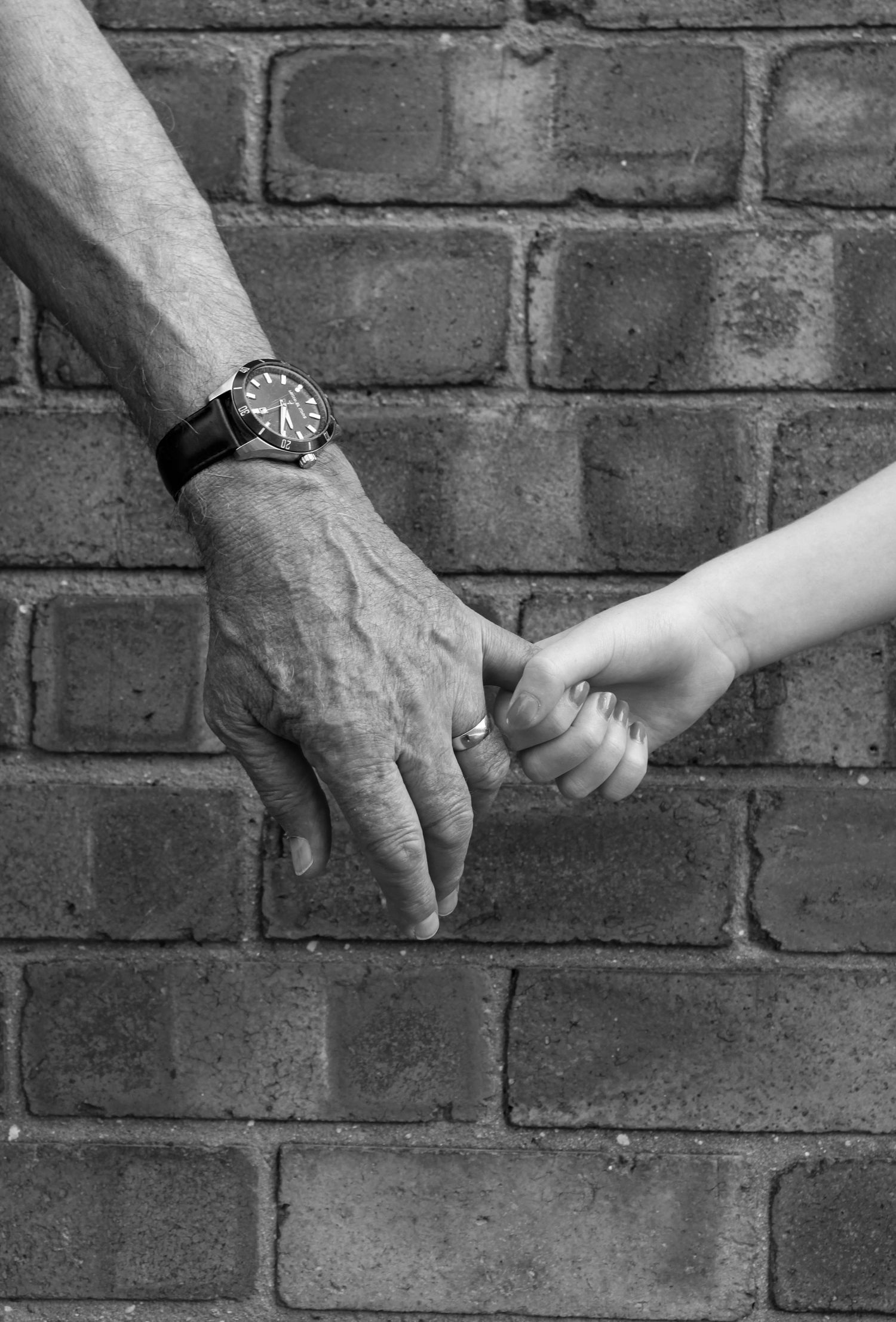 A grandparent and grandchild holding hands. Black and white.
