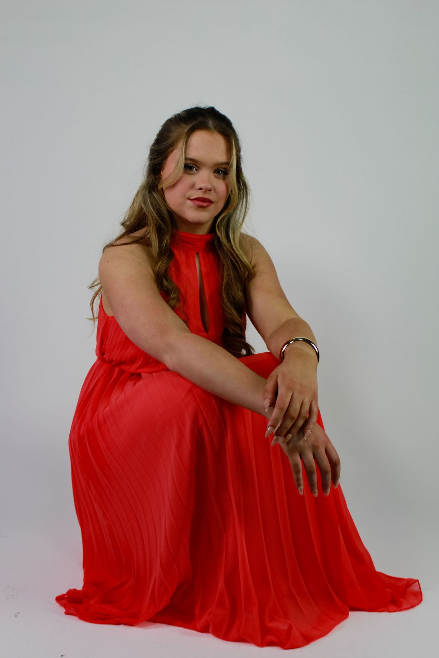 Studio portrait of a woman crouching. Fashion photo. Wearing a pink dress. Hair half up.