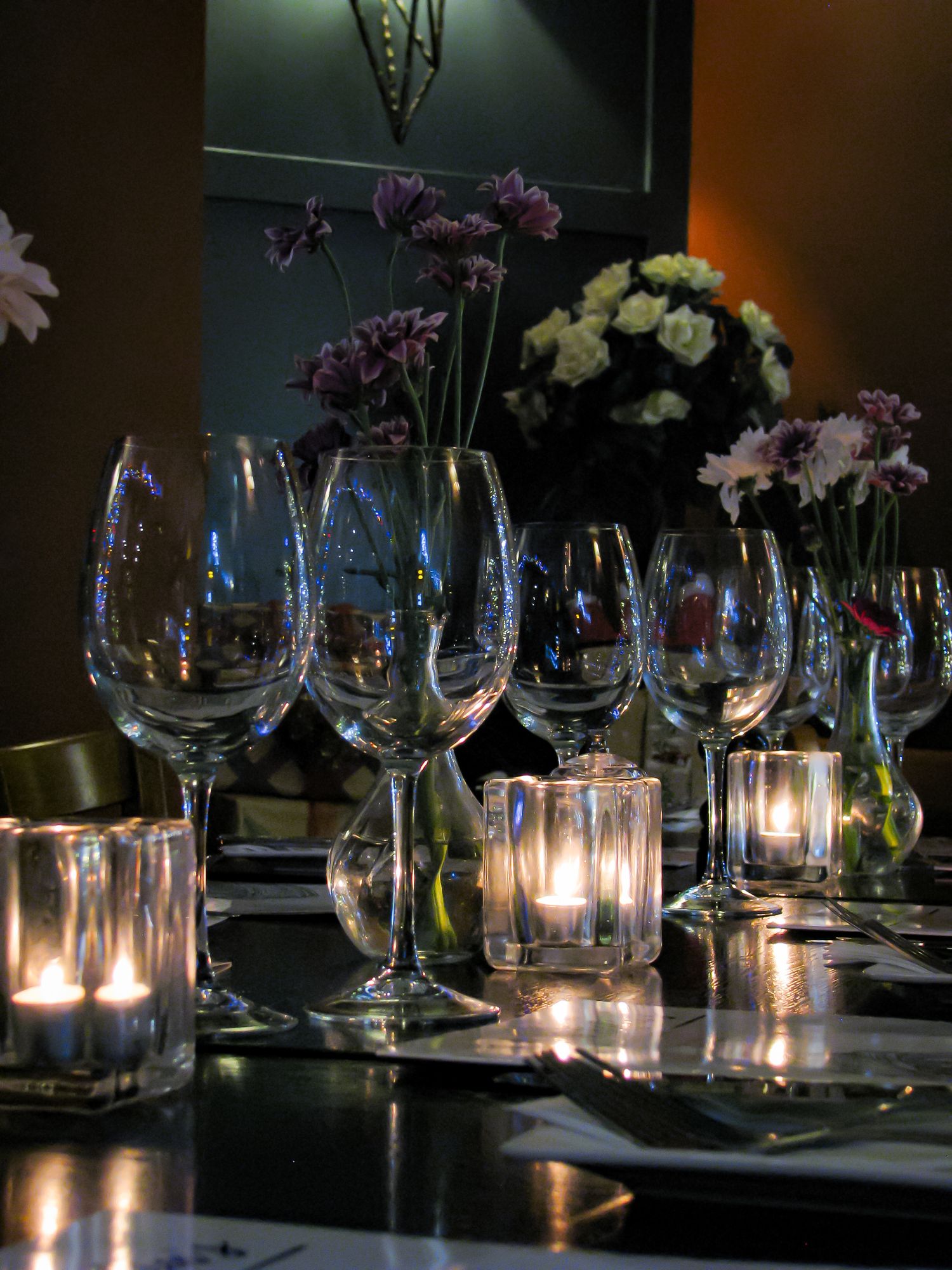Restaurant photo of a set table. Julia and Sofia’s Italian Restaurant. Christmas tree lights reflect off the glasses.