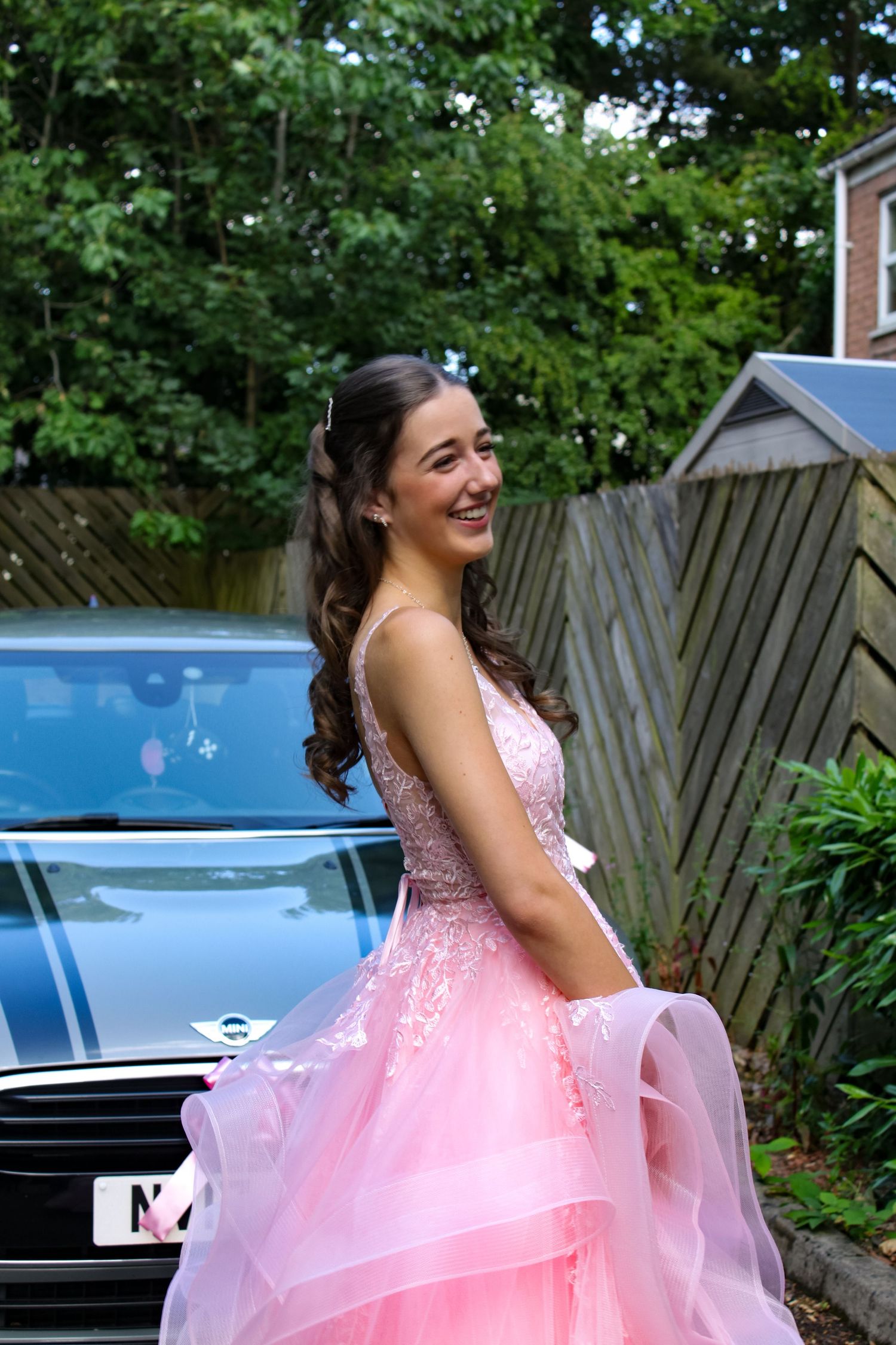 Prom portrait photo of a girl wearing her pink prom dress and smiling.