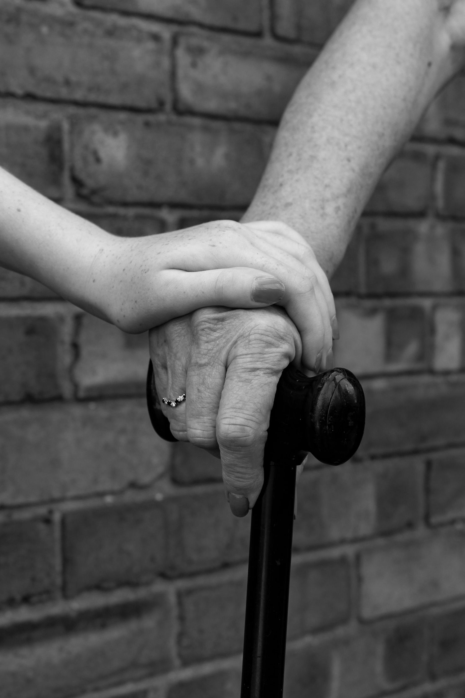 A grandparent and a grandchild holding hands. Black and white.