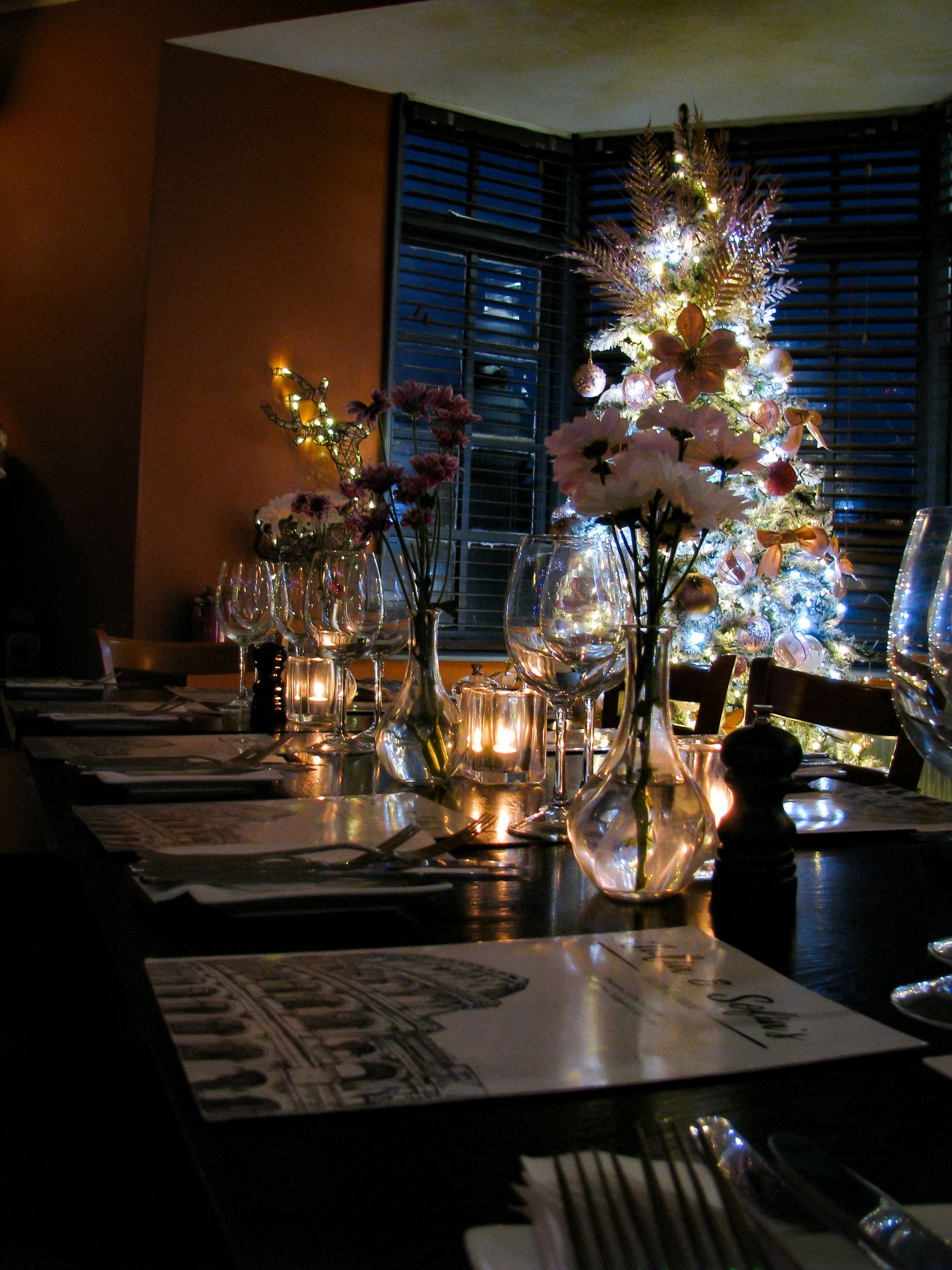 Restaurant photo of a set table with a Christmas tree in the background . Julia and Sofia’s Italian Restaurant.