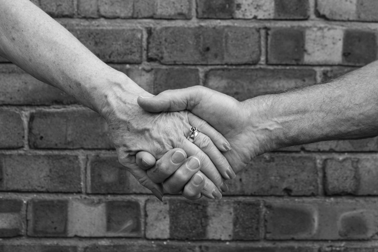 An elderly couple holding hands. Black and white.