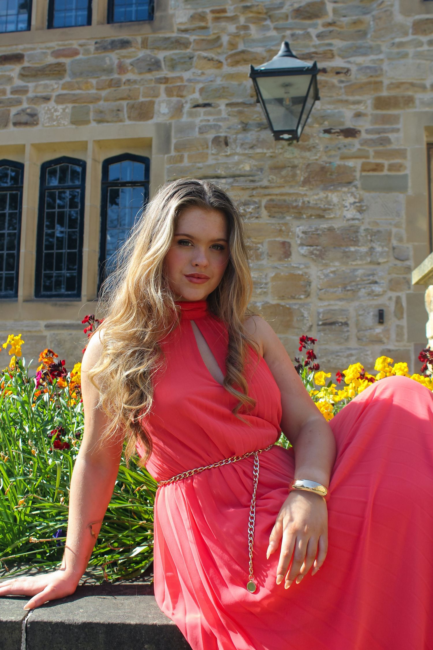 Editorial fashion portrait of a woman posed a garden with a beautiful background. Wearing her hair down and a pink dress.
