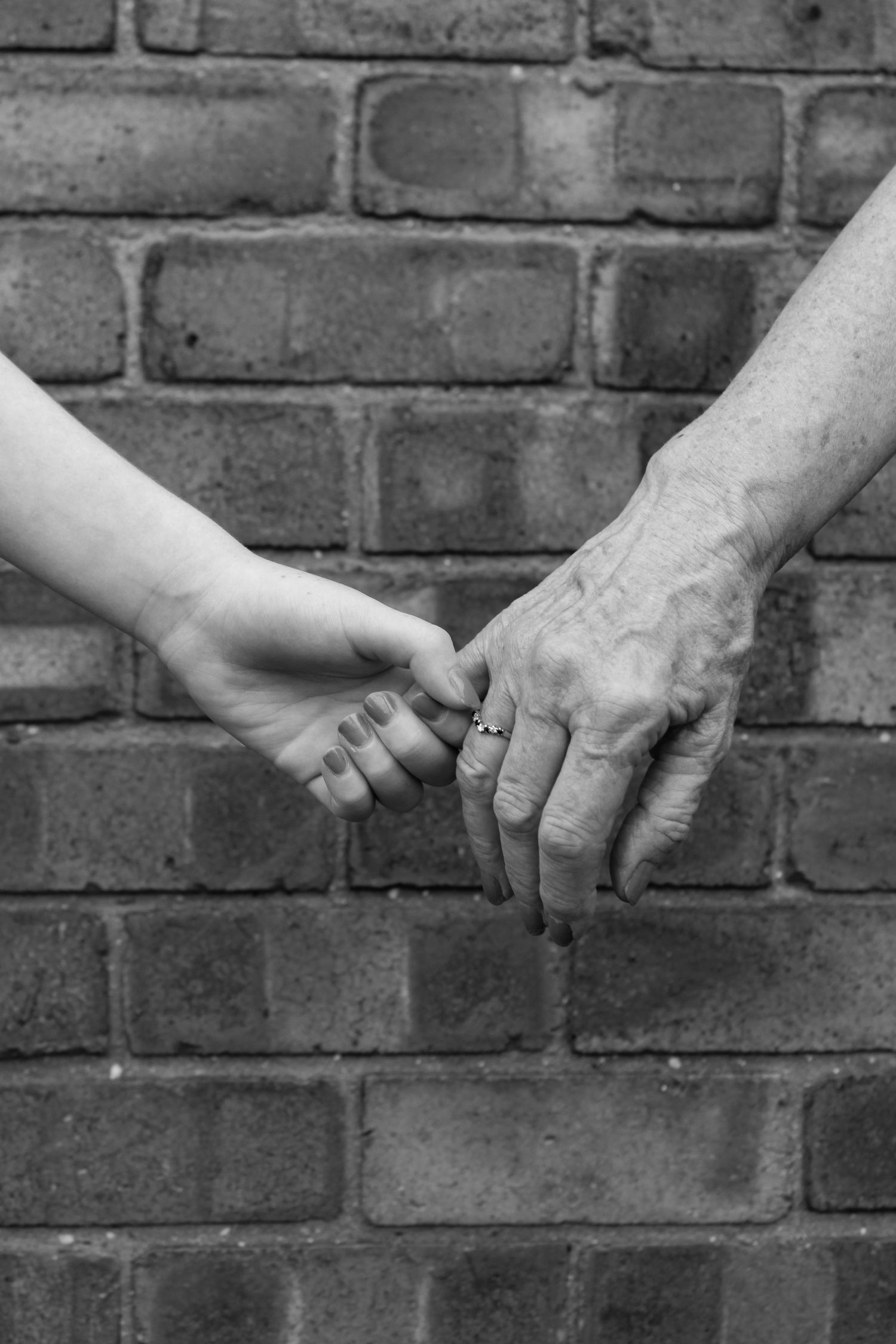 A grandparent and grandchild holding hands. Black and white.