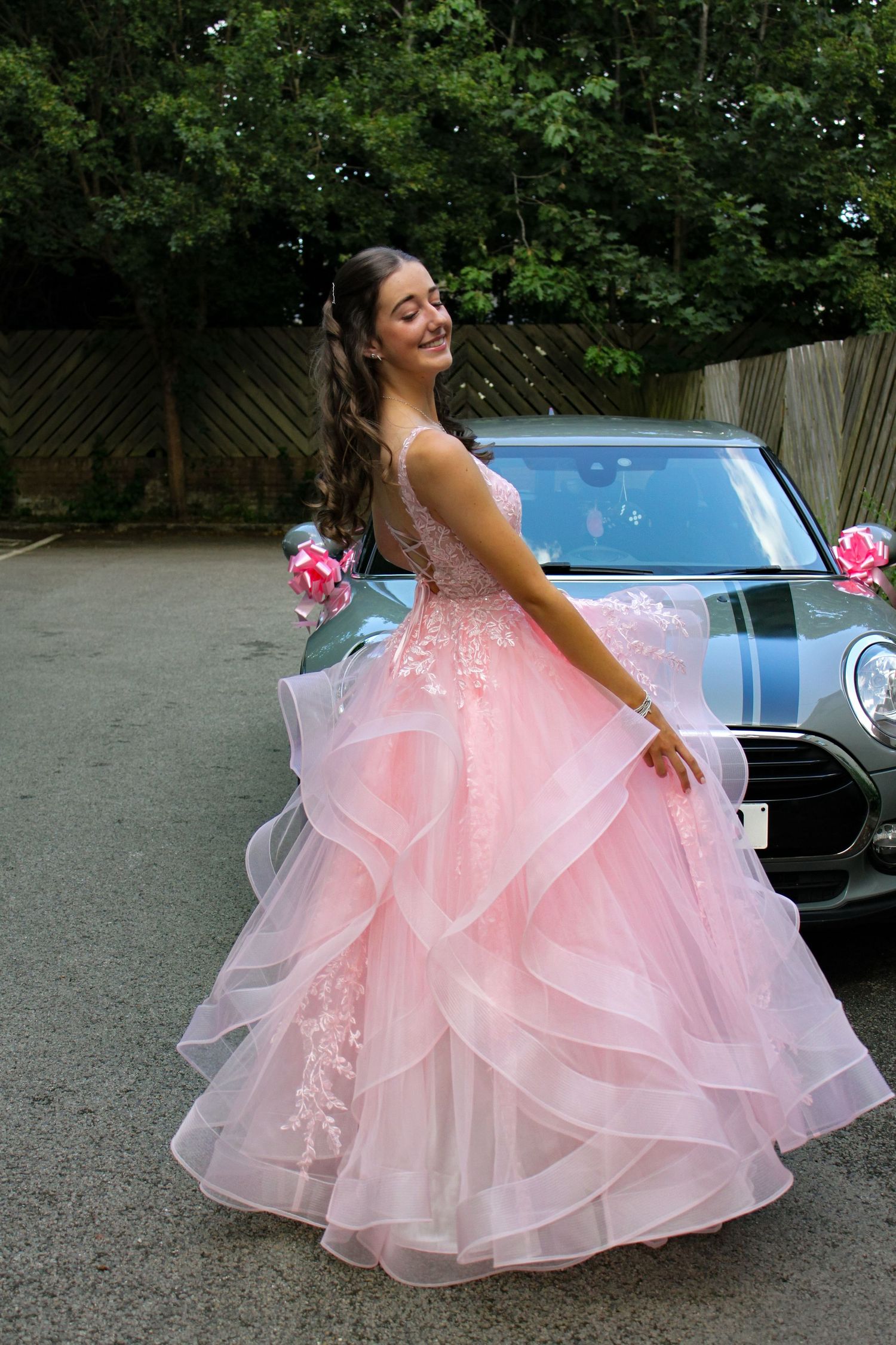 Prom portrait photo of a girl wearing her pink prom dress and smiling.