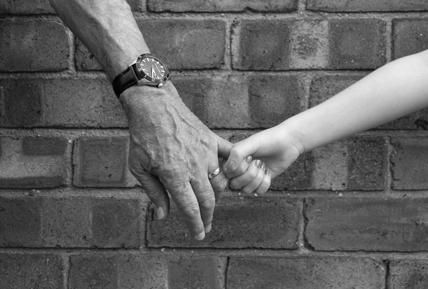 Photo of a grandparent and grandchild holding hands. Black and white.