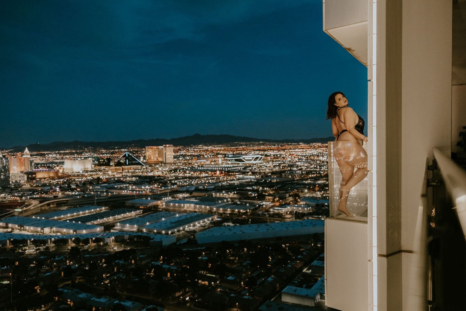 Panoramic cityscape at dusk showing twinkling lights across an urban landscape.