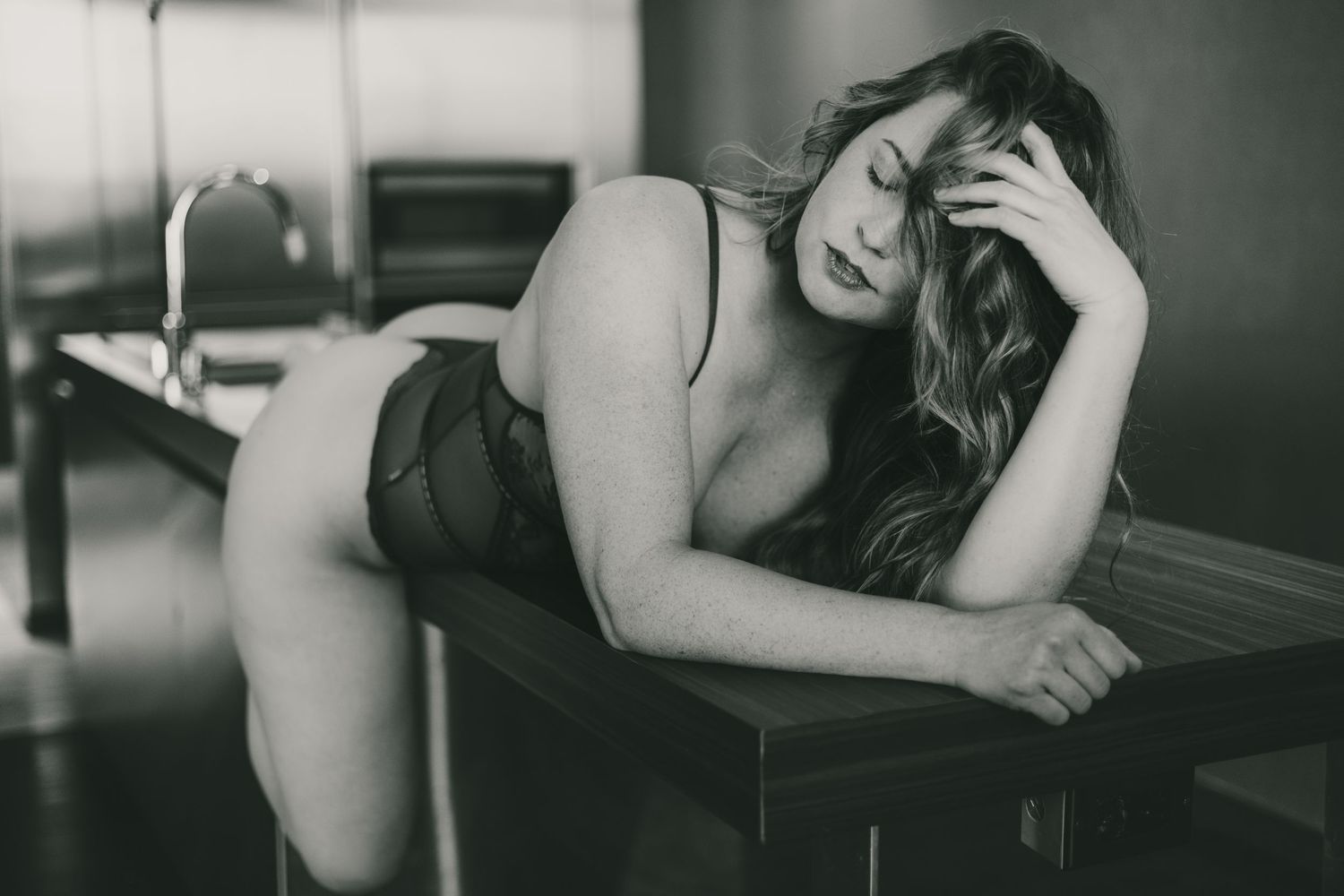 Artistic black and white photo of intimate couple lying together on bed.