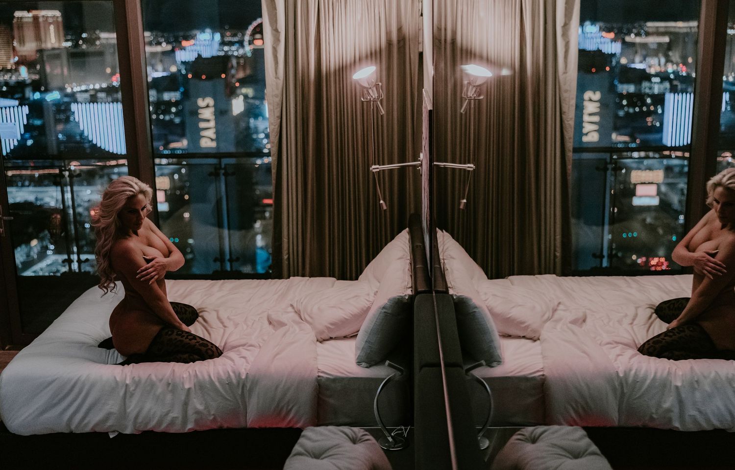 Reflective bedroom scene with city lights visible through window at night.