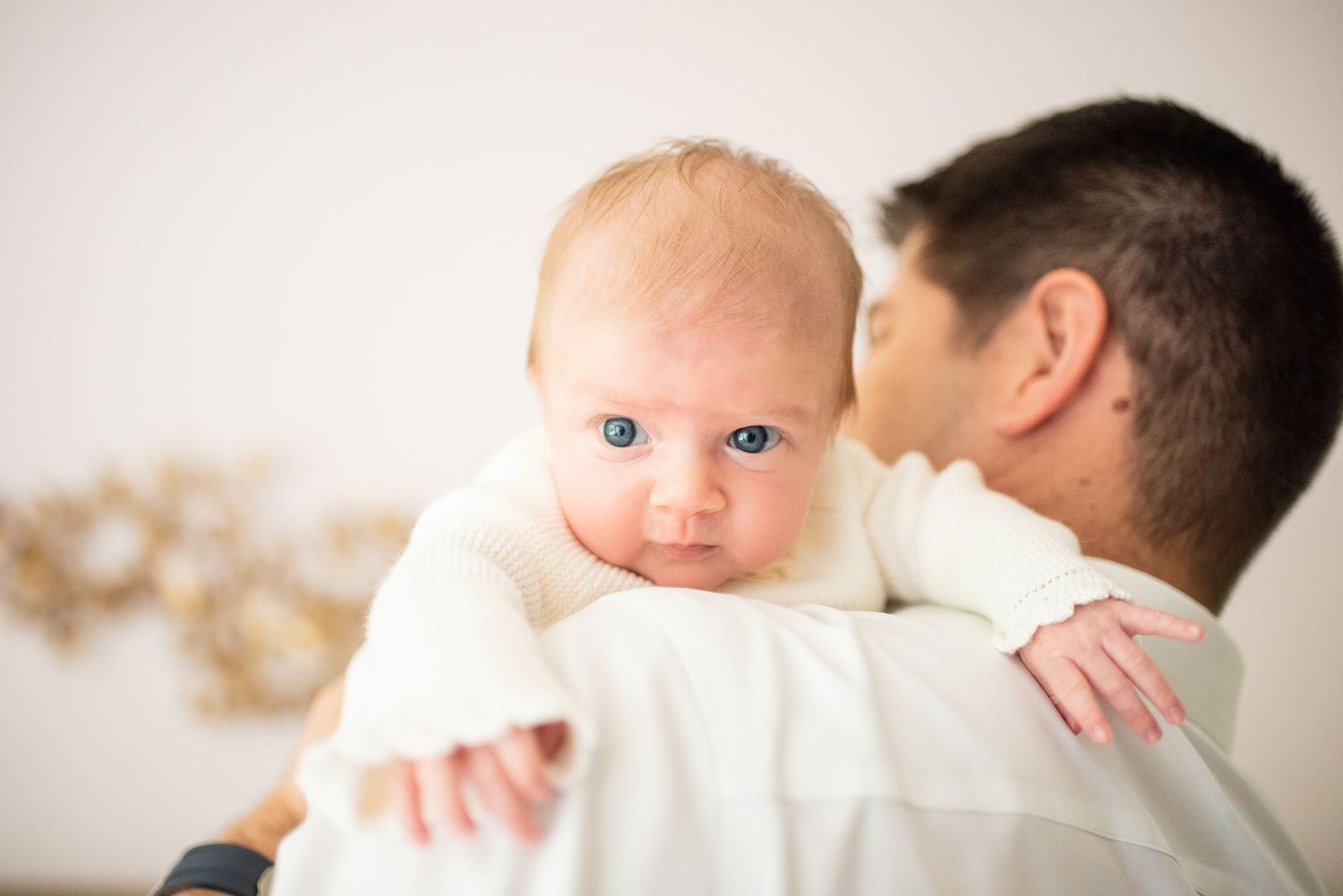 A series of tender moments showing parents holding and bonding with their newborn baby in soft, natural light.