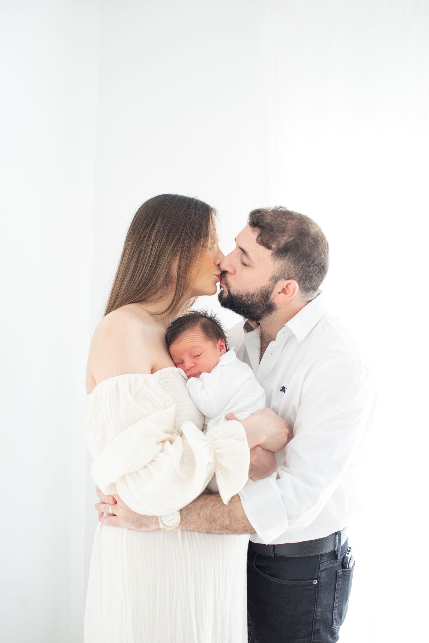 Romantic family moment captured in bright white studio with newborn.