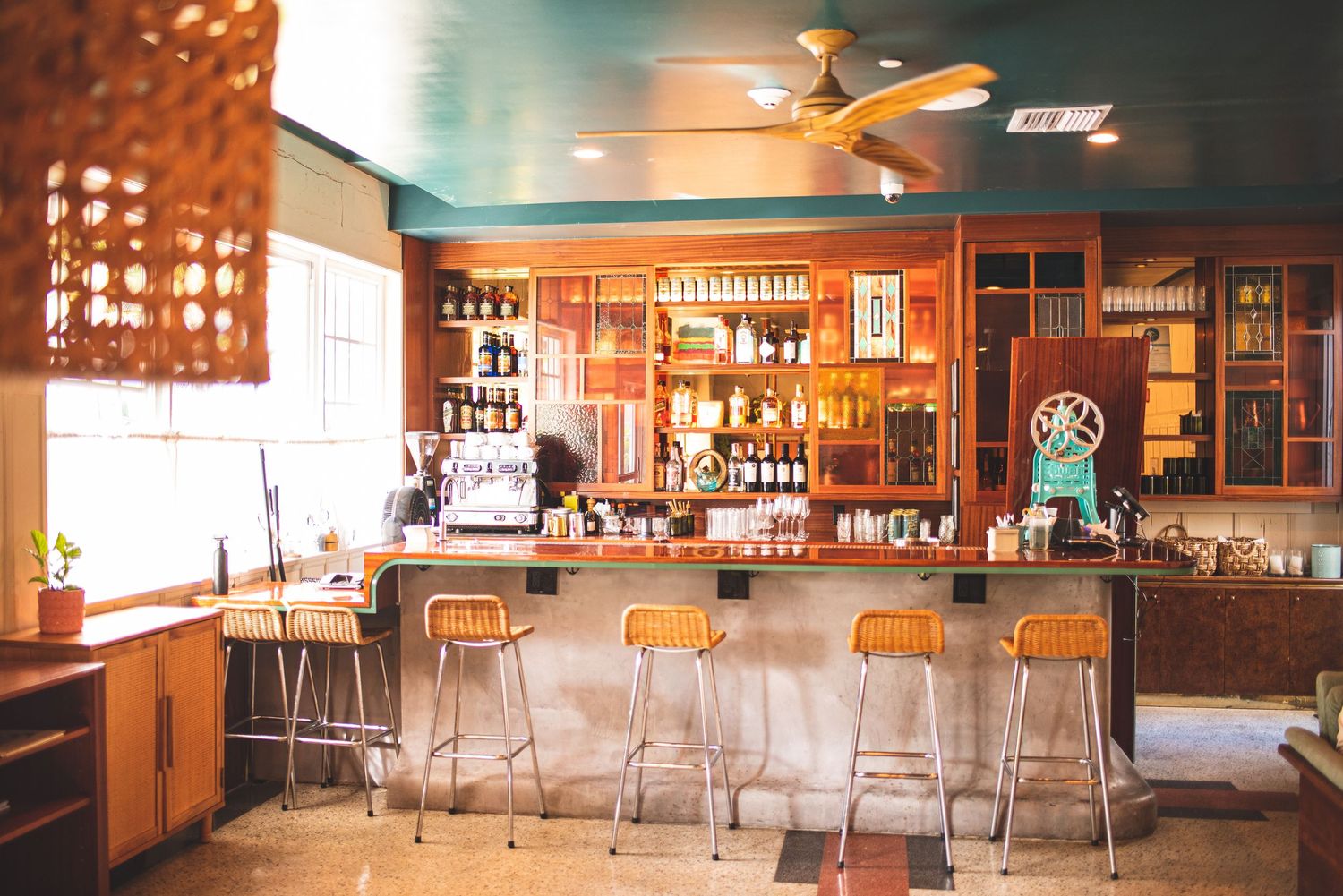 Interior view of a cozy bar with wooden furnishings, warm lighting, and multiple seating areas stretching across the space.