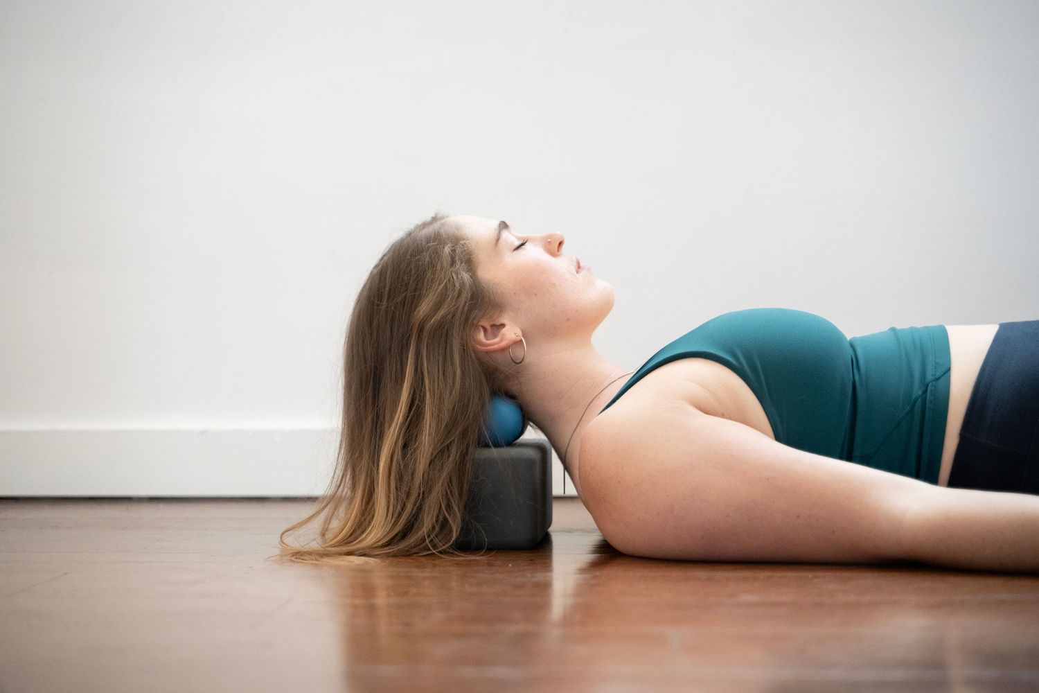 A person lies on the floor with their head tilted back in a sequence of artistic poses against a white background.