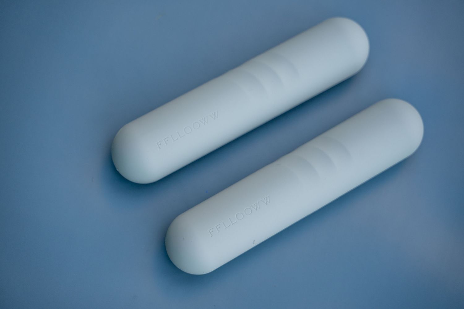 Minimalist composition of white cylindrical shapes against blue background.