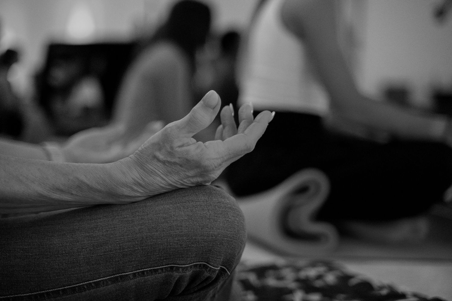 Black and white close-up of hands in meditation pose during a yoga class session.