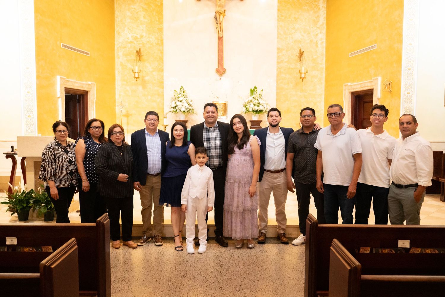 Family group photo inside a church after a First Communion ceremony, posing in front of an altar.