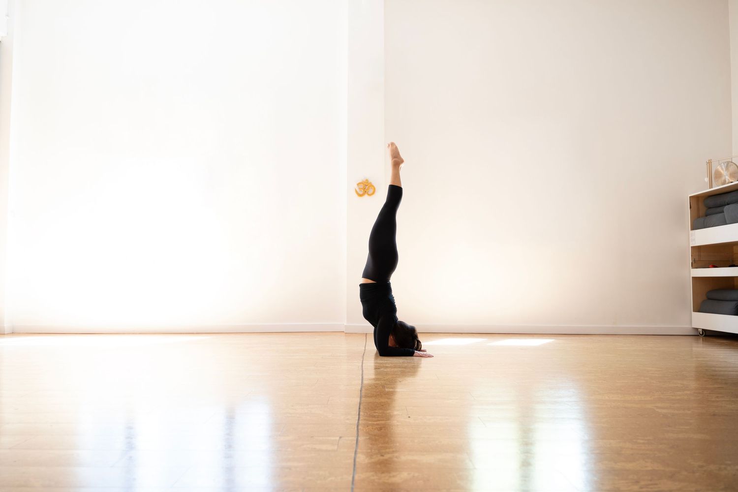 A silhouetted figure performs yoga poses in sequence against a minimalist white studio backdrop.