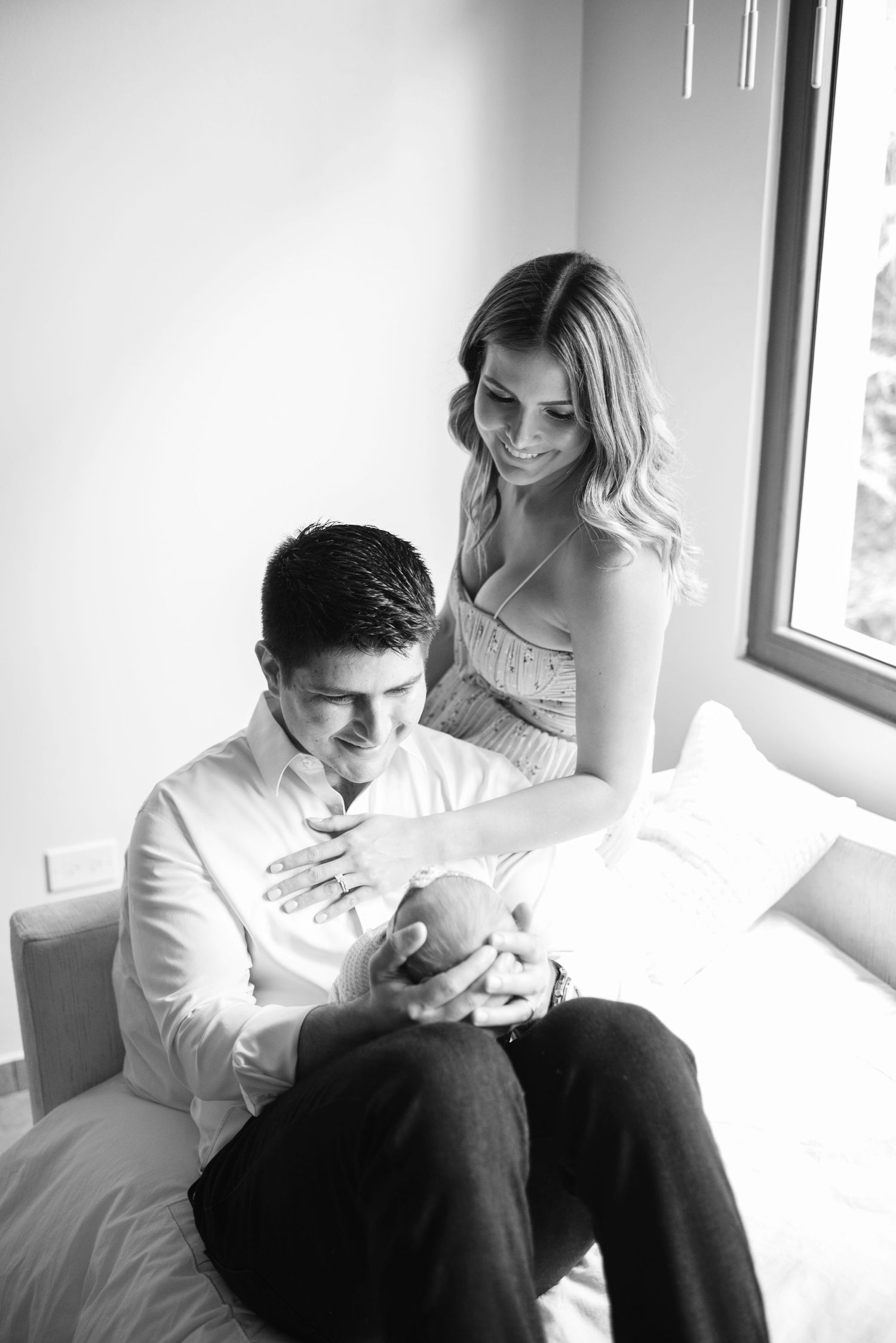 A black and white photo series showing a couple sitting together intimately by a window.