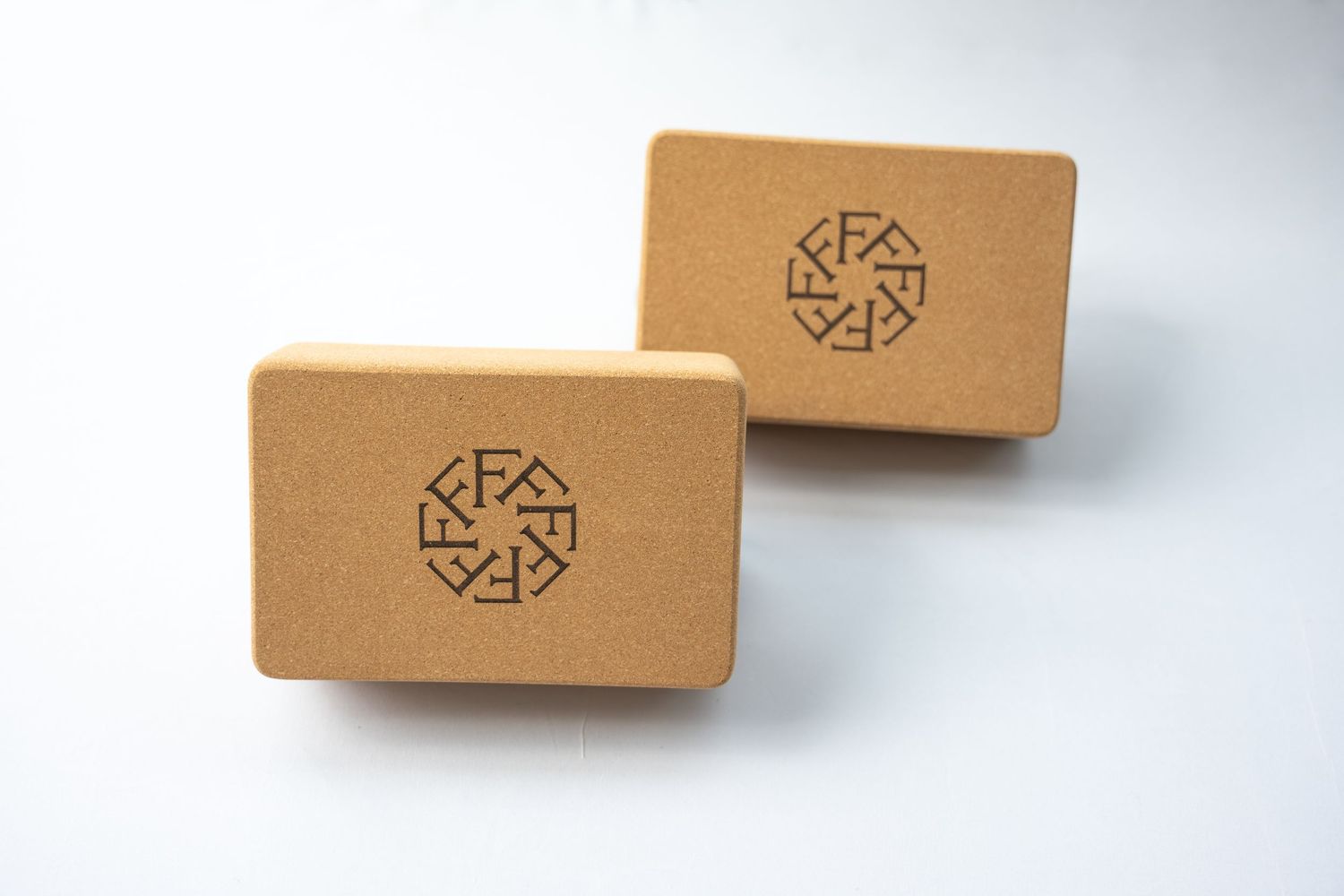 Two cork yoga blocks with geometric FFLLOWW logo imprint.