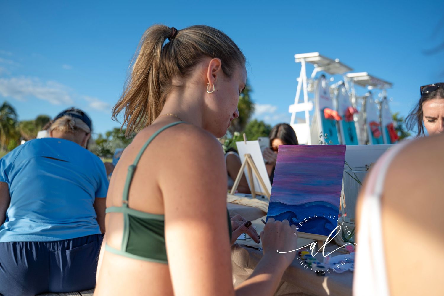 People relaxing on a boat deck with a diving platform visible in the background against a bright blue sky.
