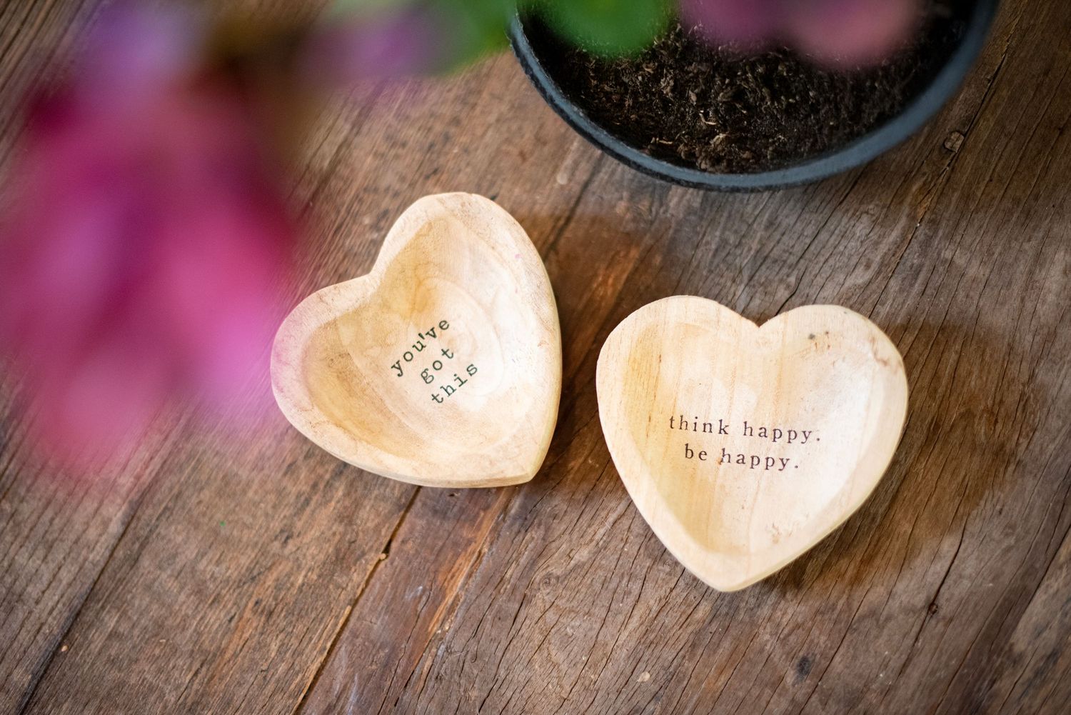 Decorative heart-shaped ceramic candle holders with text inscriptions arranged on a wooden surface.