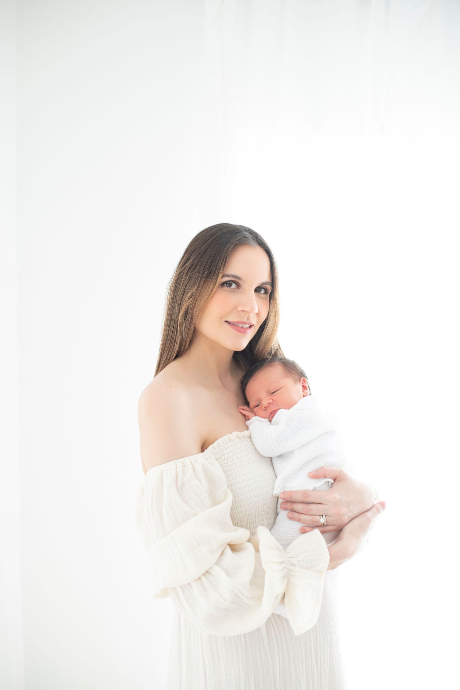 Tender moment photographed in bright white setting with flowing fabric details.