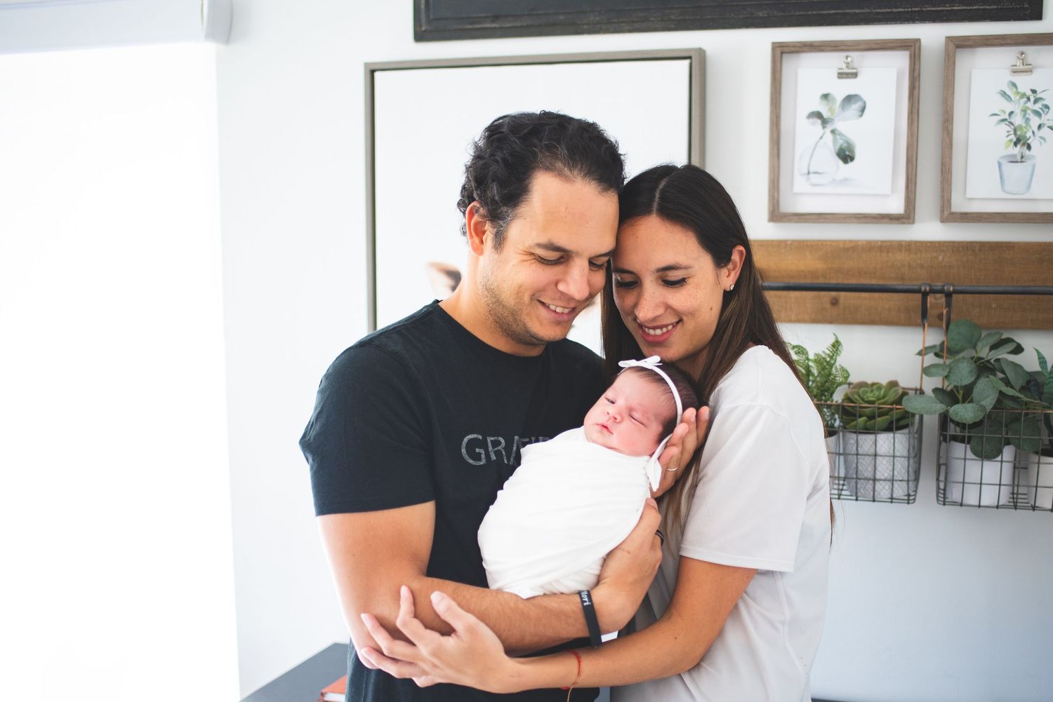 A tender moment between parents and their newborn baby in a bright, modern home setting.