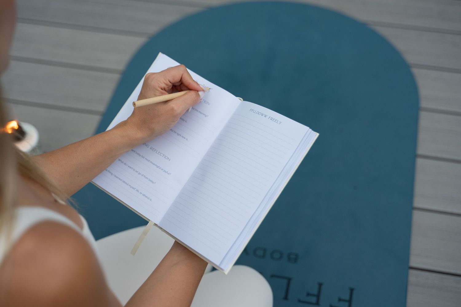 Close-up of hands writing in journal on blue surface outdoors.