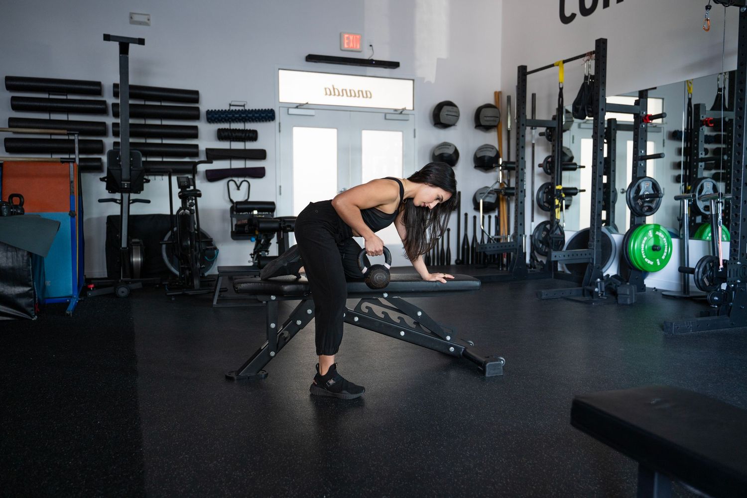 Athlete performing a dynamic lunging exercise with a barbell in a modern gym setting.
