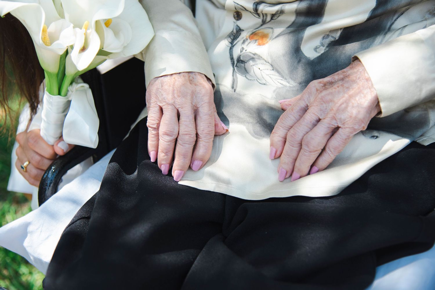 Close-up details of hands and wedding attire during outdoor celebration.
